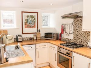 a kitchen with white cabinets and a stove top oven at 32A, Buxton in Buxton