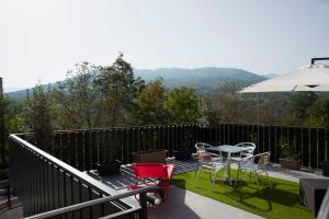 einen Balkon mit Stühlen, einem Tisch und einem Sonnenschirm in der Unterkunft B & B CA’ D’ OLINA in Pavullo nel Frignano