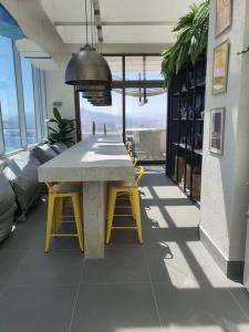 a table and two yellow chairs in a room with windows at Hermoso depto en Costa de Montemar, Vista al mar in Concón