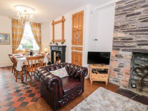 a living room with a leather couch and a fireplace at Wenallt in Caernarfon