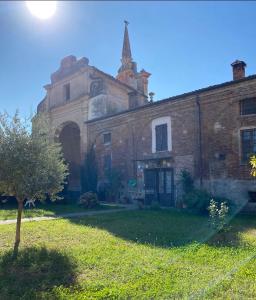 un ancien bâtiment en briques avec une église en arrière-plan dans l'établissement Il Corvo Viaggiatore, à Solarolo Monasterolo