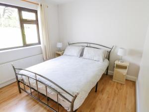 a white bed in a room with a window at Aras Iosgan in Carraroe