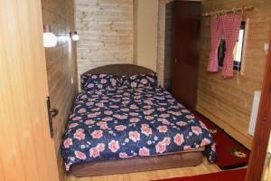 a small bedroom with a bed with a floral comforter at Brvnara Brkovic 2 in Čajetina