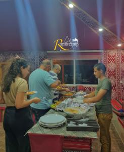 a group of people preparing food at a buffet at RUM RANIA LUXURU CAMP & Bubbles Hotel in Wadi Rum +81 photos