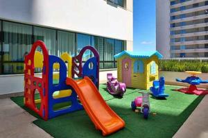 um parque infantil com equipamento de brincar em frente a um edifício em Flat Apart America Campos em Campos dos Goytacazes