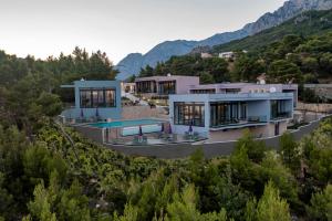 une maison sur une colline avec des montagnes en arrière-plan dans l'établissement Kuk Oaza Luxury Villas, à Makarska