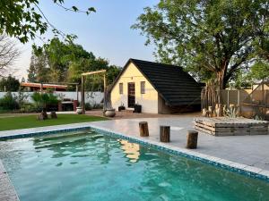 a swimming pool in front of a house at Cosy City Cottage in Gaborone
