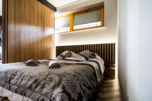 een slaapkamer met een bed met een houten muur bij Apartament Adasiowa Polana by Apart Concept Podhale in Kościelisko