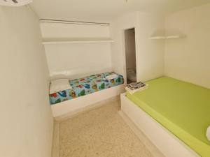 a small room with a green and white bed at El Faro Hostel in Arboletes