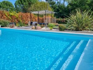 duży niebieski basen z altaną w obiekcie La Cabane au Carbet Piscine chauffée au calme dans la nature w mieście Sainte-Eulalie-en-Born