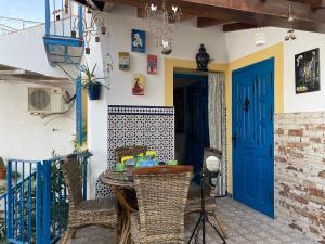a patio with a table and chairs and a blue door at CASA MARUJA WiFi 300MB & JACUZZI in Cútar