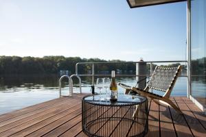 a table and chairs on a dock with a bottle of wine at JULIA - Schwimmendes Apartment in Berlin
