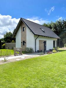 a small white house with a grass yard at BURSZTYNOWA-PRZYSTAŃ in Lubiatowo