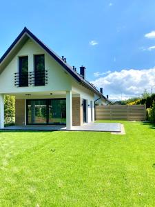 a house with a green lawn in front of it at BURSZTYNOWA-PRZYSTAŃ in Lubiatowo