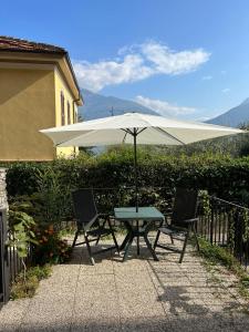 a table and two chairs with an umbrella at LakeView LakeComo 4Seasons, Terrace, 30m to Lake! by STAYHERE-LAKECOMO in Acquaseria