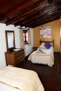 a bedroom with two beds and a dresser and a mirror at Hotel Rural Finca La Hacienda in Los Silos