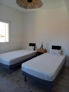 two beds in a room with a chandelier at Le Quatorze in Bollène +11 photos