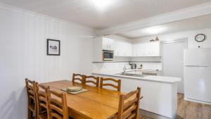 a kitchen with a wooden table and a white refrigerator at Ocean Spirit, 1 - 89 Yamba St in Yamba