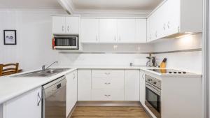 a white kitchen with white cabinets and a sink at Ocean Spirit, 1 - 89 Yamba St in Yamba