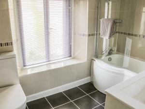 a bathroom with a tub and a toilet and a sink at 8 Stonegate in High Bentham