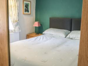 a bedroom with a bed and a table with a lamp at 8 Stonegate in High Bentham