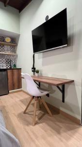 a desk with a white chair and a television on a wall at Inmueble cerca al estadio NID204 By Roots Rentals in Medellín +6 photos