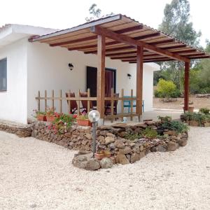 una casa con una pared de piedra y una pérgola de madera en Casa di Campagna, en Galtellì