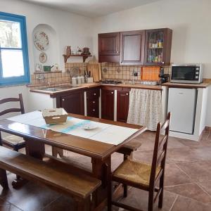 une cuisine avec une table et des chaises en bois ainsi qu'une table. dans l'établissement Casa di Campagna, à Galtellì