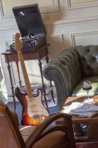 une guitare assise sur une table à côté d'un canapé dans l'établissement Cit'Hôtel Le Plantagenet, à Chinon