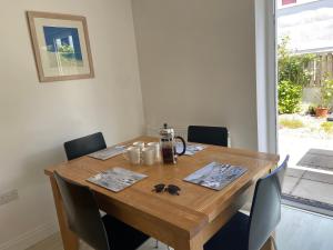 a dining room table with chairs and a wooden table at Above the Bay - Enclosed garden apartment with parking in Penzance
