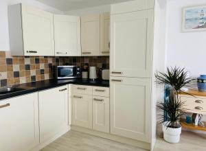 a kitchen with white cabinets and a black counter top at Above the Bay - Enclosed garden apartment with parking in Penzance