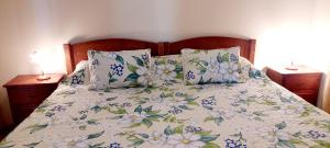 een bed met een bloemdekbed en kussens erop bij Apartamentos Villa in Ponta do Sol