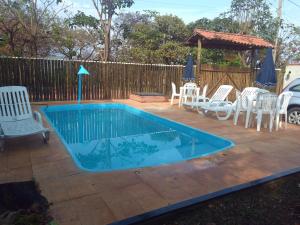 a swimming pool with chairs and a gazebo at Casa das orquídeas in Santana do Riacho