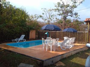 a group of white chairs and tables next to a pool at Casa das orquídeas in Santana do Riacho