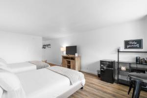 Duas camas num quarto com uma secretária e uma televisão. em Silver Sands Motel em Westport