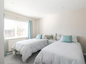 two beds in a white room with a window at Sunnyside in Wells next the Sea