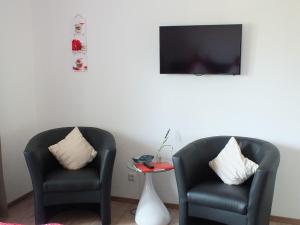 two chairs and a table with a tv on a wall at Gästehaus Müller in Bad Schonborn