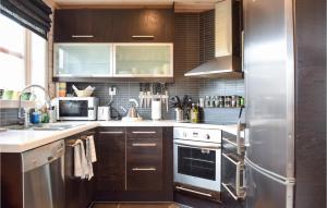 una cucina con mobili in legno e un frigorifero in acciaio inossidabile di Cozy Home In Norheimsund With Sauna a Norheimsund