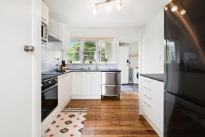 a kitchen with white cabinets and black appliances at Lake, mountain view cottage - near major attractions in Rotorua
