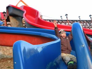 ein kleines Kind auf einer Rutsche auf einem Spielplatz in der Unterkunft Pension Valea Mariei in Ranca