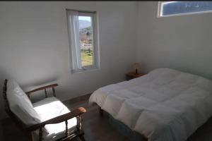 um quarto com uma cama, uma cadeira e uma janela em B&B Cerro Krund em Ushuaia