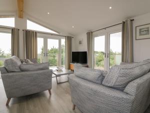 a living room with two chairs and a flat screen tv at 7 Faraway Fields in Liskeard