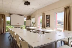 a conference room with tables and chairs and a screen at Sure Hotel by Best Western Nantes Saint-Herblain in Saint-Herblain
