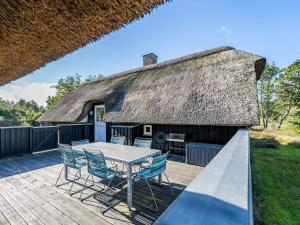 a patio with a table and chairs and a thatch roof at Holiday home Nørre Nebel XLIX in Nørre Nebel