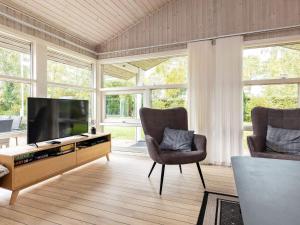 uma sala de estar com 2 cadeiras e uma televisão de ecrã plano em Holiday home Otterup XVIII em Otterup