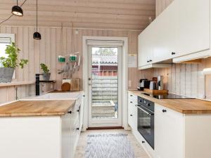 カーテミンドにある5 person holiday home in Kertemindeの木製の壁と白いキャビネット、ドアが備わるキッチン
