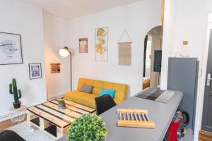 ein Wohnzimmer mit einem Tisch und einem gelben Sofa in der Unterkunft Appartement T2 au calme Cosy - Quartier Prébendes in Tours