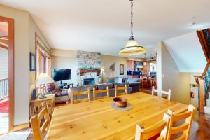 een eetkamer en een woonkamer met een houten tafel bij Blacksmith Lodge 2 in Big White