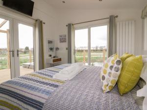 a bedroom with a bed with pillows and windows at 11 Meadow Retreat in Liskeard