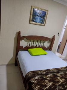 a bedroom with a wooden bed with a yellow pillow at Hospedagem da Val in Angra dos Reis